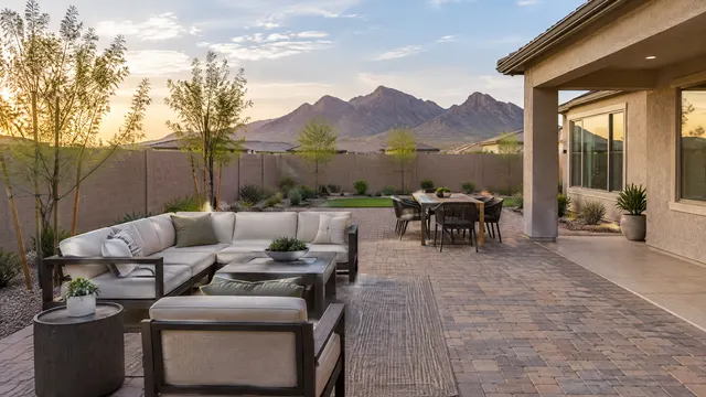 New paver patio behind a newer single-story home in Laveen, Phoenix with a block wall, young trees and the Estrella mountains in the distance
